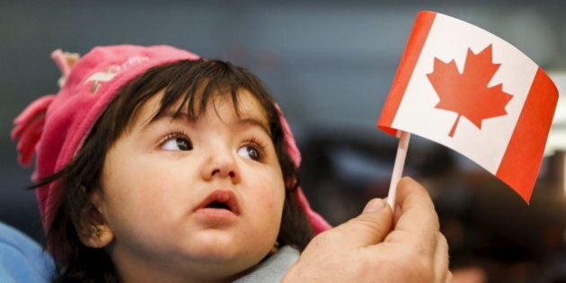 A young Syrian refugee looks up as her father holds her and a Canadian flag at the as they arrive at Pearson Toronto International Airport in Mississauga, Ontario, December 18, 2015. REUTERS/Mark Blinch TPX IMAGES OF THE DAY