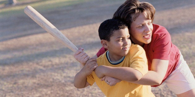 Mother helping son sing a baseball bat