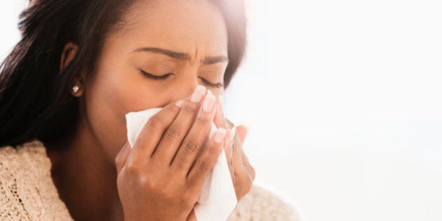 Mixed race woman blowing her nose