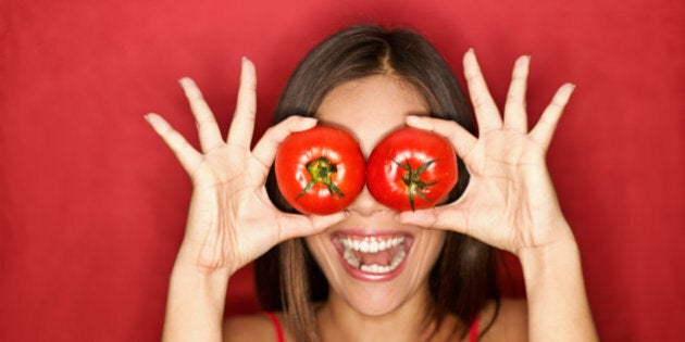 Tomato. Woman showing tomatoes holding them in front of eyes. Fresh energetic funny image on red background. See more