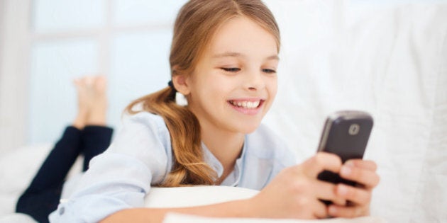education, school, technology and internet concept - little student girl with smartphone at home