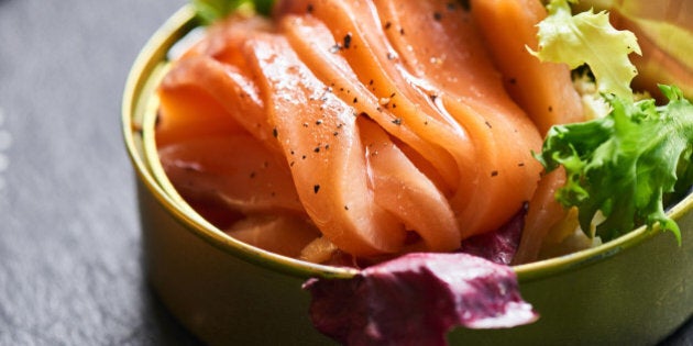 Poorly salted salmon served in a tin and crispy baguette on a stone plaque closeup