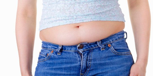 A woman's stomach bulging over the waistband of her jeans.