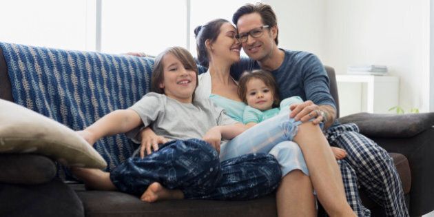 Affectionate family in pajamas relaxing on sofa