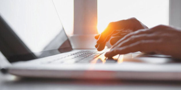 Close-up of male hands typing on laptop keyboard