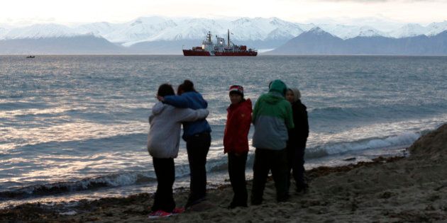 Local children stand on the shore as the Coast Guard ship Des Groseilliers sits in the waters near the Arctic community of Pond Inlet, Nunavut August 23, 2014. Picture taken August 23, 2014. REUTERS/Chris Wattie (CANADA - Tags: MILITARY POLITICS)