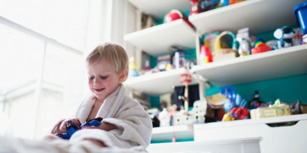 Boy sitting in bed in his room playing with toy