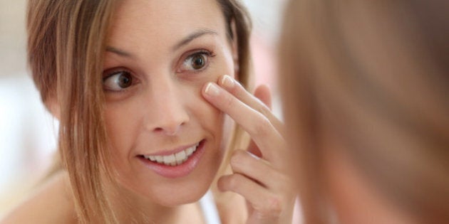 Attractive girl putting anti-aging cream on her face