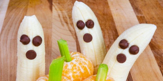 Halloween child friendly treats with bananas and clementines made to look like pumpkins and ghosts
