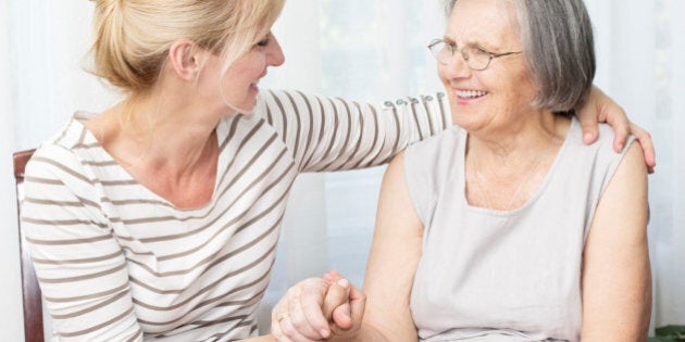 Beautiful mature daughter holding hands her senior mother.