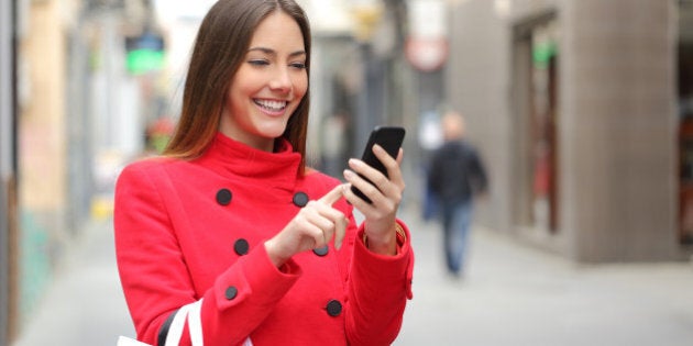 Shopper woman buying online on the smart phone in the street