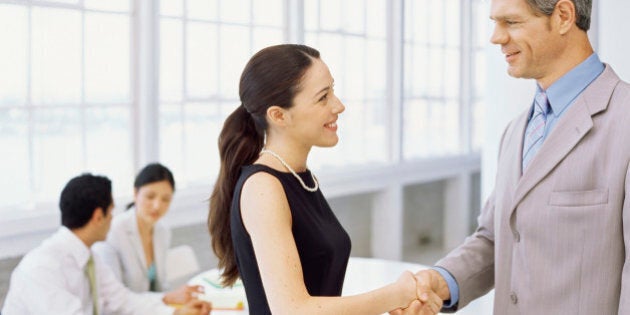 side profile of a businesswoman and a businessman shaking hands