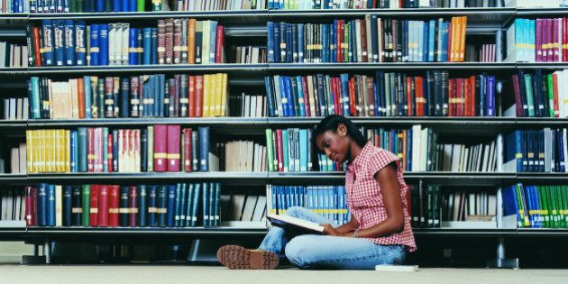 Female University Student Sitting on a Library Floor Reading a Book