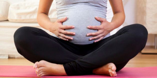 Close-up of pregnant woman sitting cross-legged on exercise mat