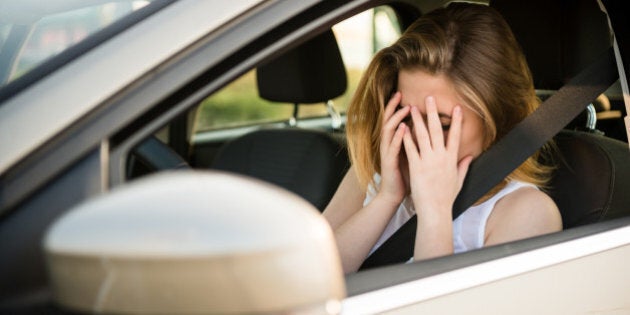 Young woman with head in hands sitting in car