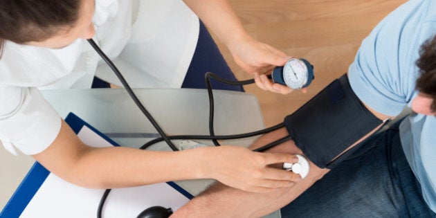 Close-up Of Female Doctor Checking Blood Pressure Of Male Patient