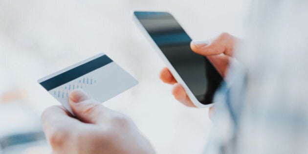 Closeup young man hands holding credit card and using cell, smart phone for online shopping or reporting lost card, fraudulent transaction