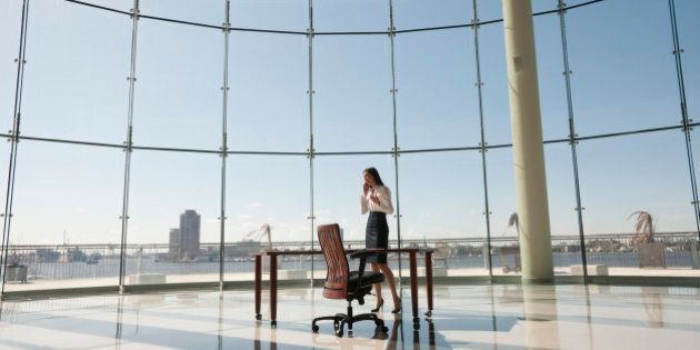 Businesswoman working in large office with glass wall