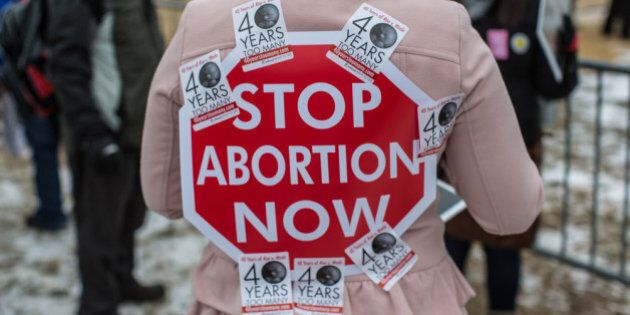 WASHINGTON, DC - JANUARY 25: An anti-abortion protester has a sign stuck to her back with stickers at the March for Life on January 25, 2013 in Washington, DC. The pro-life gathering is held each year around the anniversary of the Roe v. Wade Supreme Court decision. (Photo by Brendan Hoffman/Getty Images)