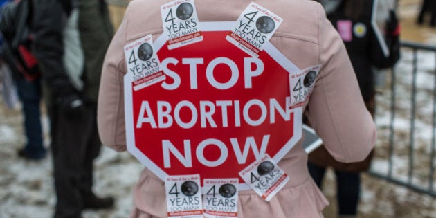 WASHINGTON, DC - JANUARY 25: An anti-abortion protester has a sign stuck to her back with stickers at the March for Life on January 25, 2013 in Washington, DC. The pro-life gathering is held each year around the anniversary of the Roe v. Wade Supreme Court decision. (Photo by Brendan Hoffman/Getty Images)