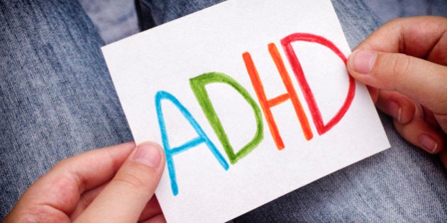 Young boy holds ADHD text written on sheet of paper. ADHD is Attention deficit hyperactivity disorder. Close up.