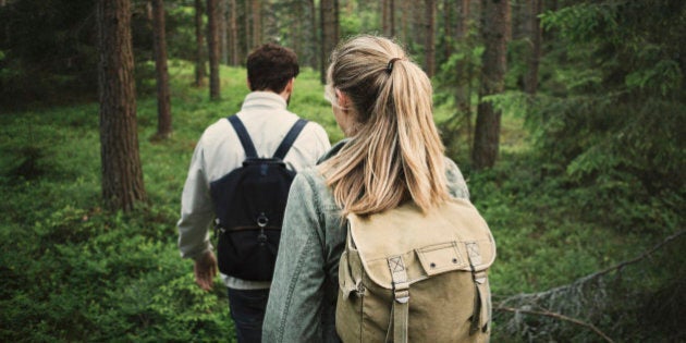 Rear view of wonderlust couple walking through forest