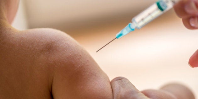 Doctor injecting a young child with a vaccination or antibiotic in a small disposable hypodermic syringe.