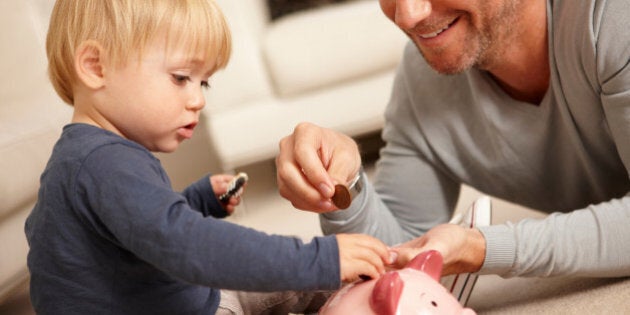 Father and son putting coins in piggy bank