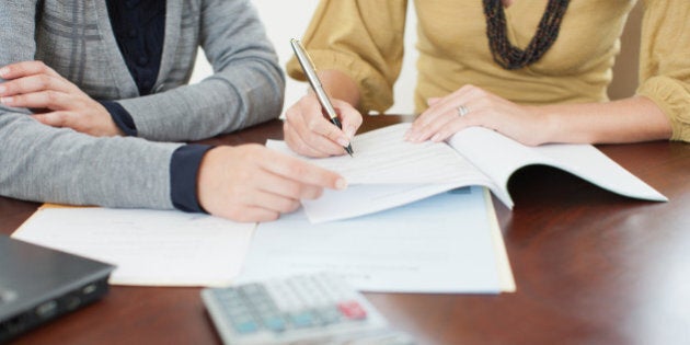 Businesswoman watching woman sign paperwork