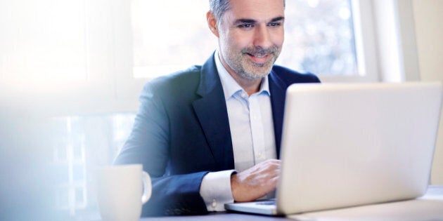 Businessman working on a laptop smiling.