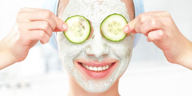 Funny young girl with a mask for skin face and cucumbers on eyes