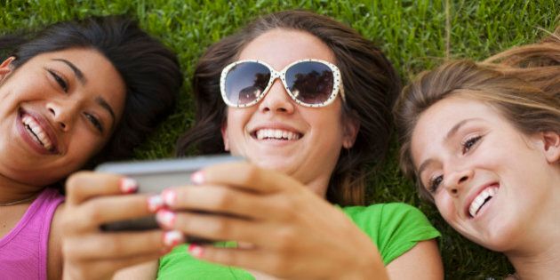 Friends laying in grass looking at cell phone