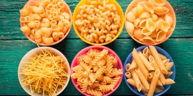 Various mix of pasta on wooden rustic background. Diet and food concept.