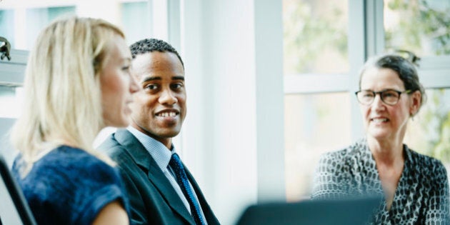 Smiling businessman listening to businesswoman lead discussion during meeting