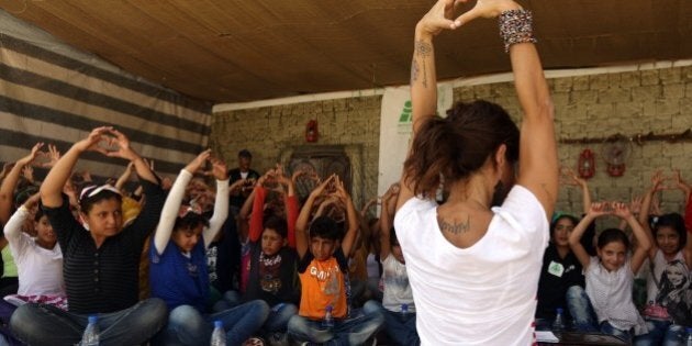 Lebanese Yogi Danielle Abi Saab and Syrian schoolchildren flash the love sign during an introductory yoga course organised by Abi-Saab and the Non-Governmental Organization Beyond with the support of the UNICEF, at a makeshift school for Syrian refugees near the town of Zahle, in Lebanon's Bekaa Valley, on October 01, 2015 AFP PHOTO/PATRICK BAZ (Photo credit should read PATRICK BAZ/AFP/Getty Images)