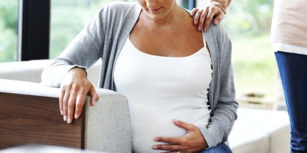 Woman comforting her friend looking worried about her pregnancy