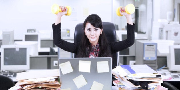 Young businesswoman doing exercise in front of her laptop with lots of sticky notes