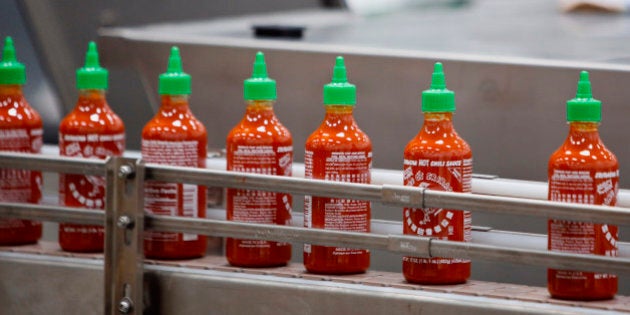 Bottles of the Sriracha hot sauce travel down a conveyor belt to be boxed for shipment at the Huy Fong Foods Inc. facility in Irwindale, California, U.S., on Monday, Nov. 11, 2013. A judge denied the city of Irwindale's request for a temporary restraining order and set a hearing for November 22 to determine whether the hot-sauce factory should be shut down while it fixes alleged odor problems. Photographer: Patrick T. Fallon/Bloomberg via Getty Images