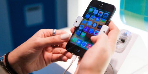 A customer inspects an Apple Inc. iPhone 5 smartphone inside a Portugal Telecom SGPS SA mobile communications store in Lisbon, Portugal, on Wednesday, Oct. 2, 2013. Portugal Telecom SGPS SA, the country's biggest phone company, agreed to merge with Brazilian affiliate Oi SA, creating a carrier with almost $17 billion in sales and 100 million customers to bulk up in Latin America. Photographer: Mario Proenca/Bloomberg via Getty Images