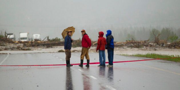 CANMORE, CANADA - JUNE 20: Bystanders look over debris deposited by Cougar Creek as it flowed up and over the TransCanada Hiway after it was closed June 20, 2013 in Canmore, Alberta, Canada. Widespread flooding caused by torrential rains washed out bridges and roads prompting the evacuation of thousnds. (Photo by John Gibson/Getty Images)