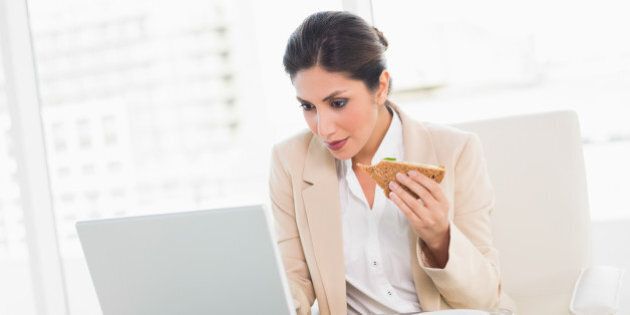 Focused businesswoman eating lunch as she is working at the office