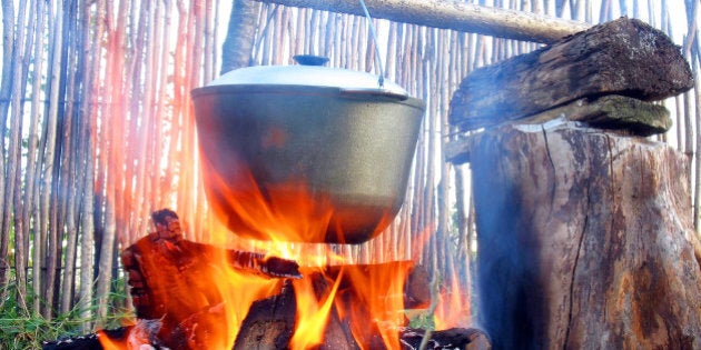 The kettle on a wooden crossbeam hangs over a fire