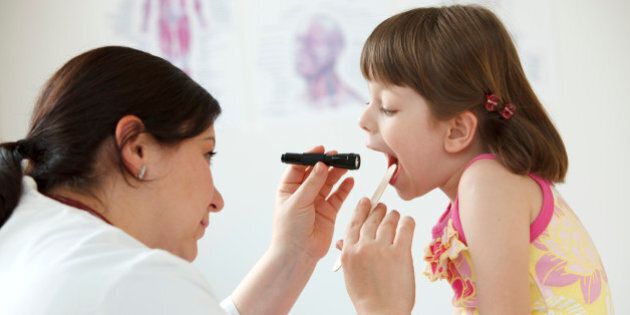Female pediatrician checking child's throath