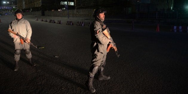 Afghan policemen block a road near the security perimeter of the Serena hotel in Kabul early on March...