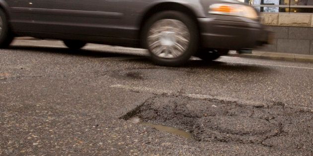 Downtown traffic passes a pothole in Portland, Ore., Thursday, Feb 11, 2010. If you live in Portland and spot a nasty pothole, burned-out streetlight or noxious graffiti, Mayor Sam Adams wants you to grab your iPhone and report it.(AP Photo/Don Ryan)