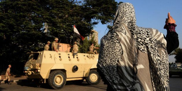 An Egyptian woman waves to soldiers on top of an armoured vehicle guarding the entrance of a military hospital where former Egyptian president Hosni Mubarak was transferred after his release from prison on August 22, 2013 in Cairo. Mubarak was sent to the military hospital after his release from prison after he was cleared for conditional release while standing trial, an interior ministry general told AFP. He will be held under house arrest at the Cairo hospital on the orders of the prime minister, who has been granted the power to order arrests during the current state of emergency. AFP PHOTO/MARWAN NAAMANI (Photo credit should read MARWAN NAAMANI/AFP/Getty Images)