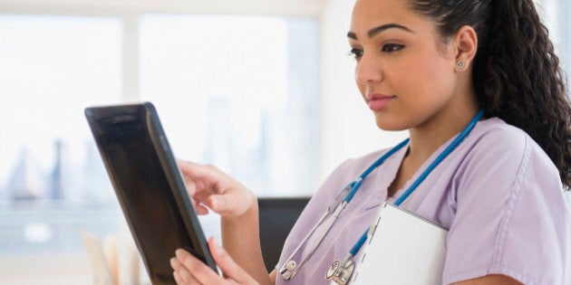 Hispanic nurse using tablet computer in hospital