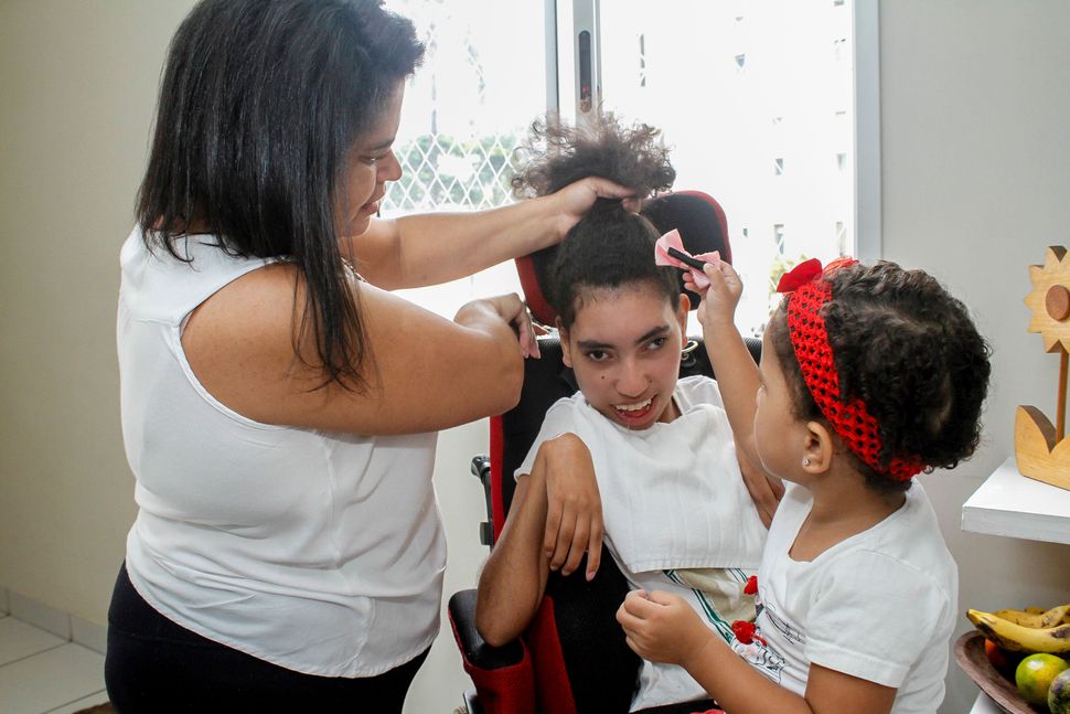 Adenilda conta com a ajuda da filha mais nova para arrumar o cabelo da irmã com paralisia