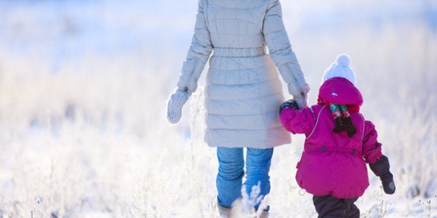 Back view of mother and daughter walking on winter day