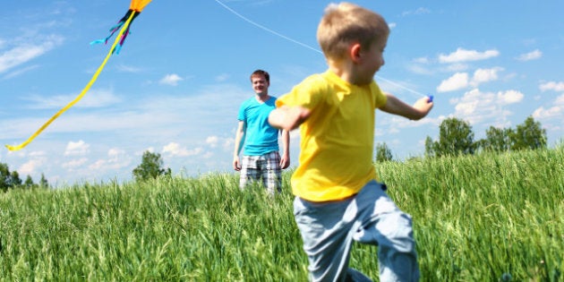 father with son in summer playing with kite